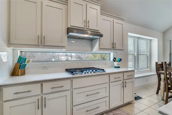 a kitchen with stainless steel appliances kitchen island granite countertop a table chairs sink and cabinets