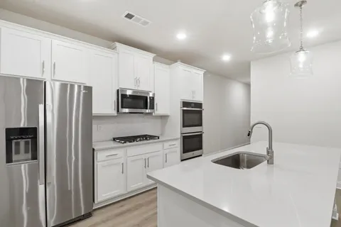 a kitchen with stainless steel appliances a refrigerator sink and microwave
