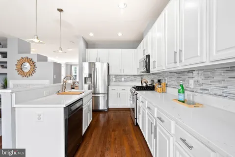 a view of kitchen island a sink and a wooden floor
