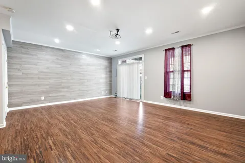 a view of an empty room with wooden floor and window