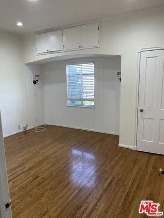 an empty room with wooden floor and cabinet