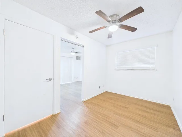 an empty room with wooden floor and ceiling fan