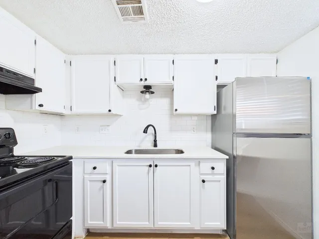 a kitchen with granite countertop a sink cabinets and stainless steel appliances