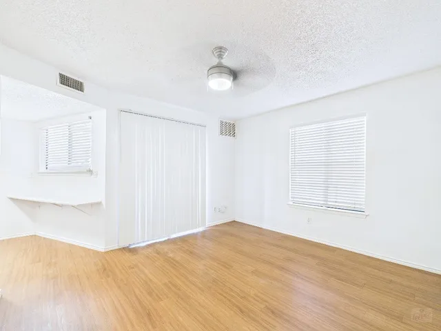a view of empty room with wooden floor and fan