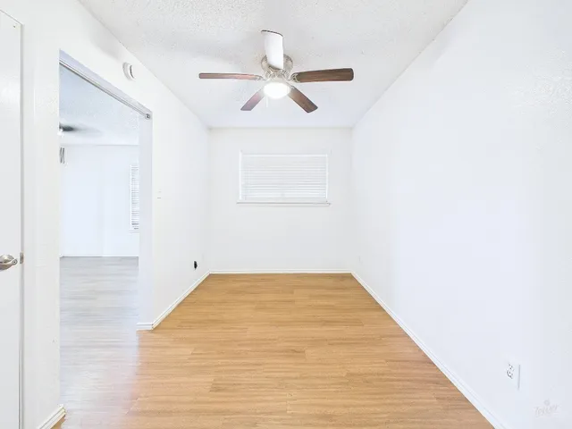 a view of a room with a ceiling fan and wooden floor