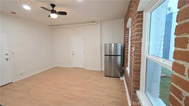 a view of empty room with windows and refrigerator