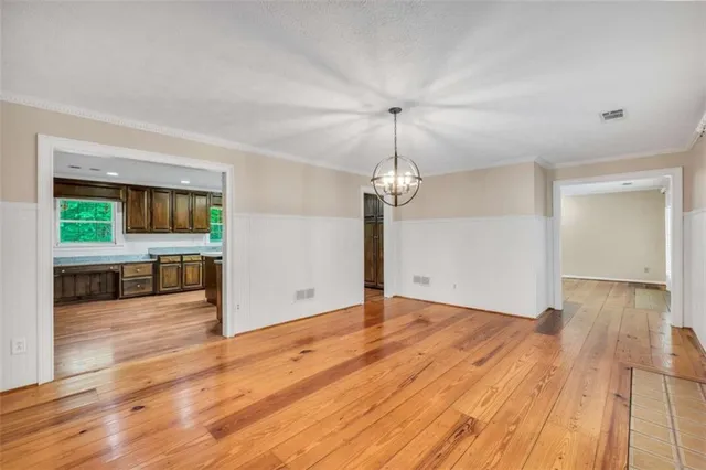 a kitchen with stainless steel appliances granite countertop wooden cabinets a sink a stove a refrigerator and island with wooden floor