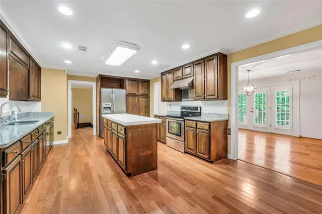 a large kitchen with stainless steel appliances lots of counter space and wooden floor