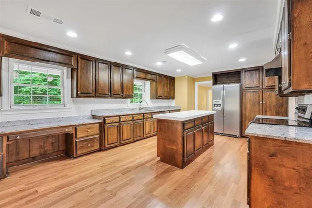 a kitchen with stainless steel appliances granite countertop wooden cabinets a sink and a large window