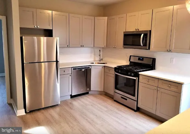 a kitchen with cabinets stainless steel appliances and wooden floor