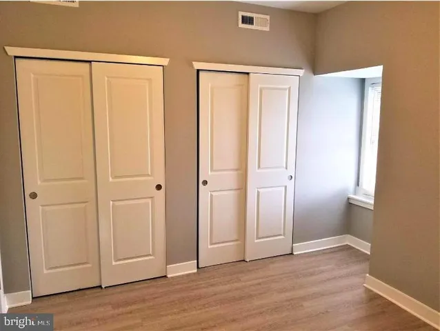 a view of an empty room with wooden floor and closet