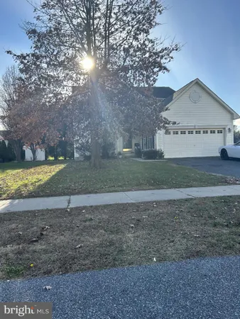 a view of a house with a yard and a large tree