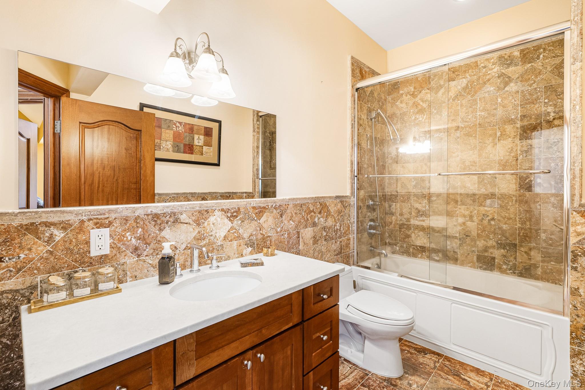33 Winding Rd Farm Ardsley, NY 10502 - Photo 28 of 50 Bathroom featuring a chandelier, vanity, enclosed tub / shower combo, and tile walls