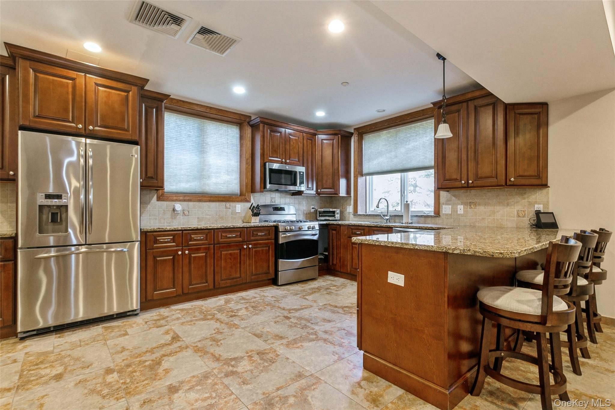 33 Winding Rd Farm Ardsley, NY 10502 - Photo 33 of 50 Kitchen with appliances with stainless steel finishes, a peninsula, decorative backsplash, a kitchen breakfast bar, and recessed lighting