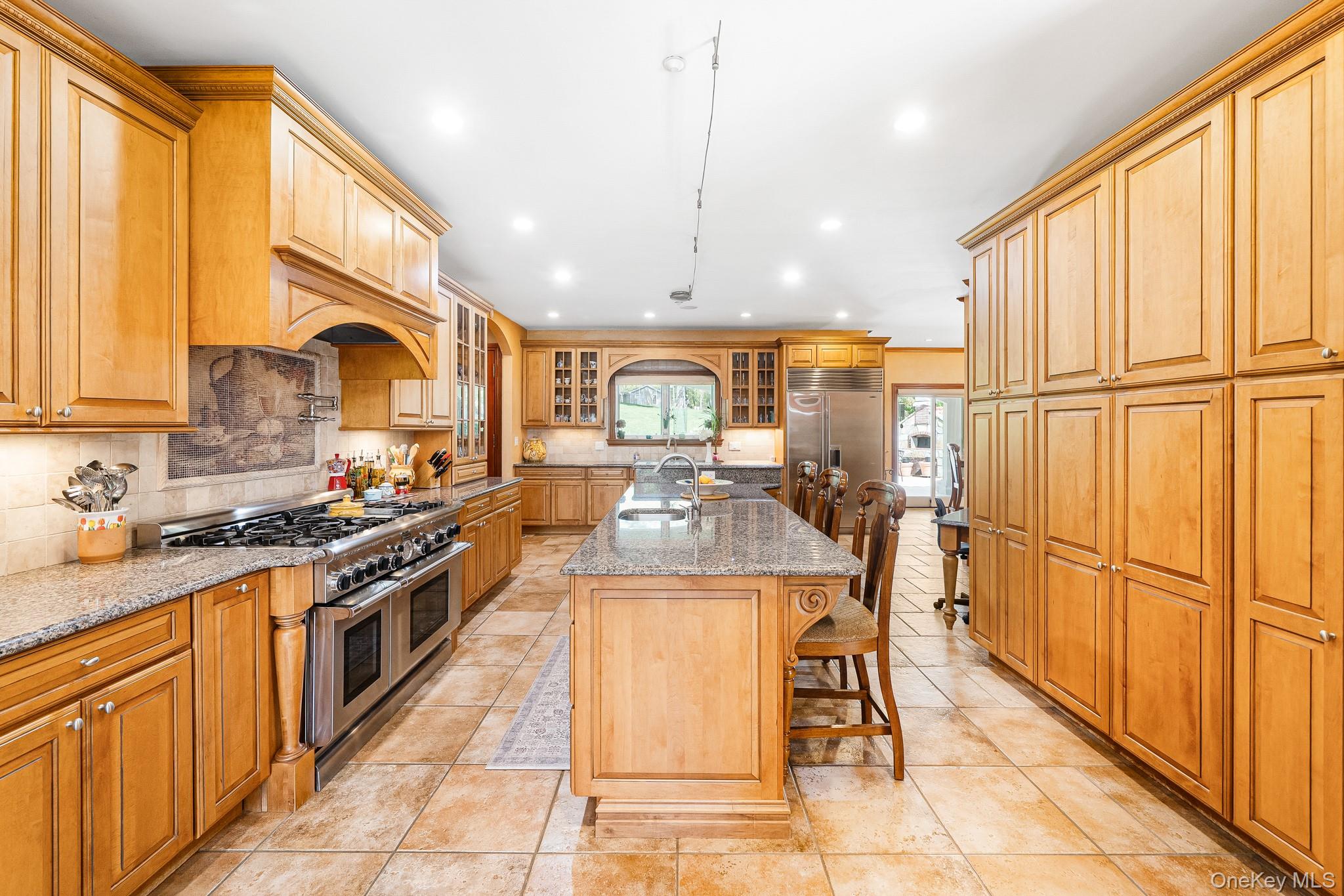 33 Winding Rd Farm Ardsley, NY 10502 - Photo 6 of 50 Kitchen featuring high quality appliances, backsplash, light stone countertops, a breakfast bar, and glass insert cabinets