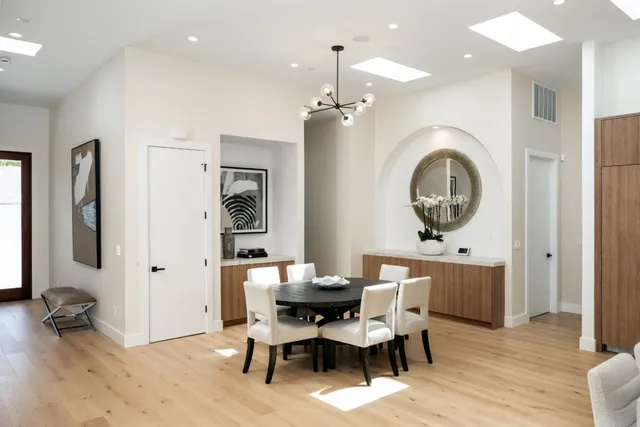a dining room with wooden floor a glass table and chairs