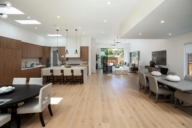 a living room with stainless steel appliances furniture a dining table and a large window