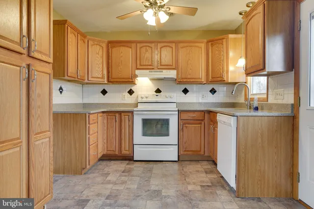 a kitchen with stainless steel appliances granite countertop a stove a sink and a refrigerator with white cabinets