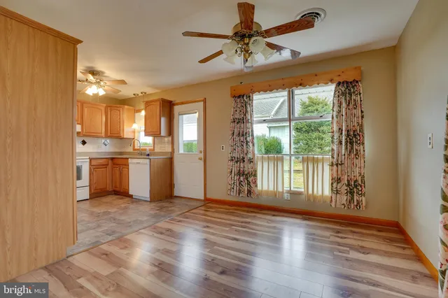 a view of a kitchen with furniture a ceiling fan and wooden floor