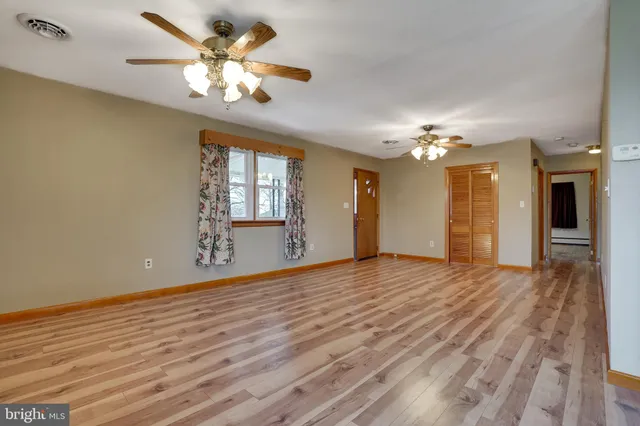 a view of an empty room with a chandelier fan and a large window