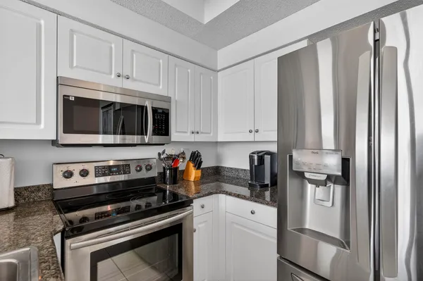 a kitchen with stainless steel appliances granite countertop a refrigerator stove and white cabinets