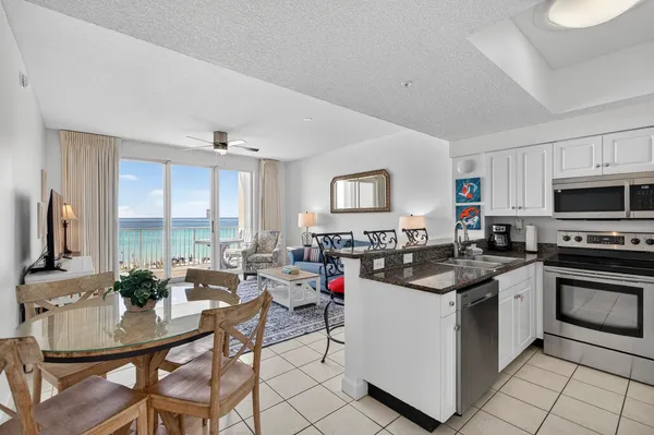 a kitchen with stainless steel appliances granite countertop a stove top oven a sink dishwasher a dining table and chairs with wooden floor
