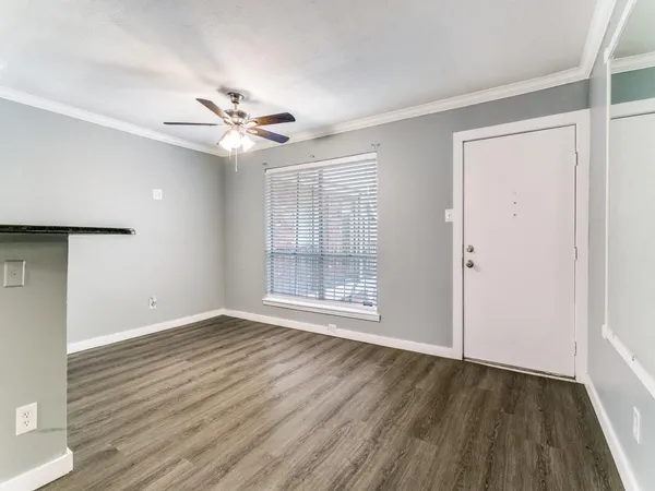 an empty room with wooden floor ceiling fan and windows