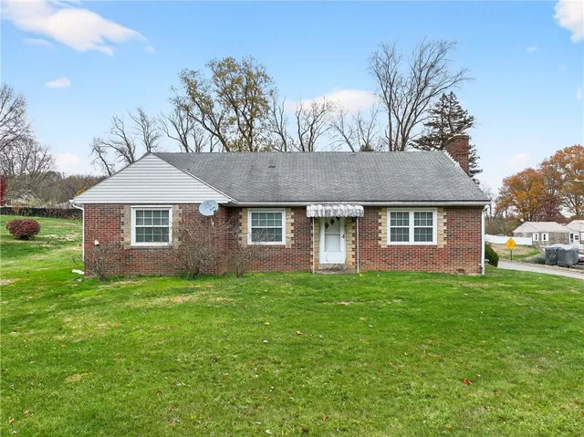 a view of a yard in front of a house with plants and large tree