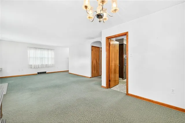 an empty room with a chandelier fan and windows