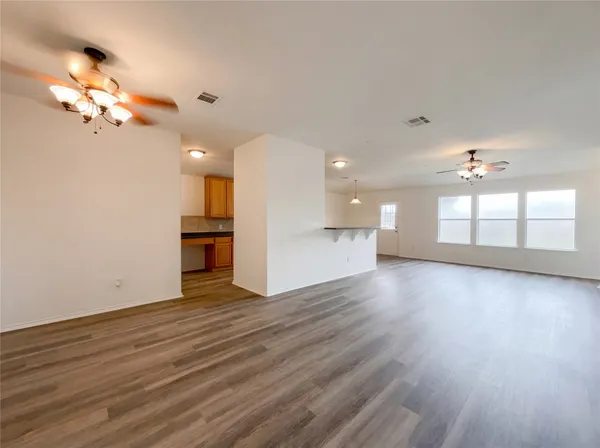 a view of an empty room with a kitchen and wooden floor