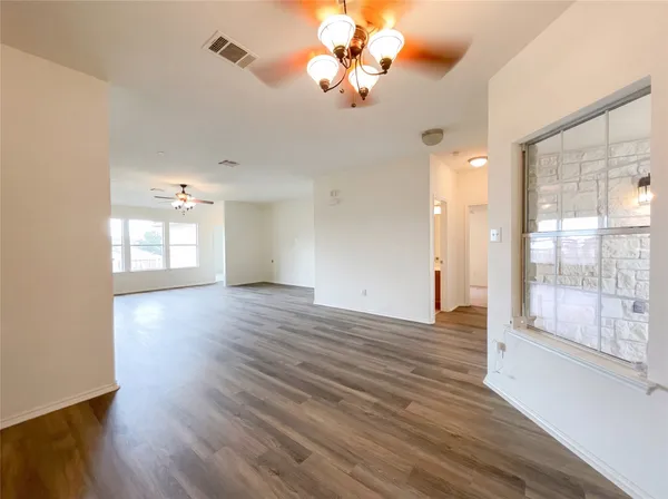 a view of an empty room with window and wooden floor