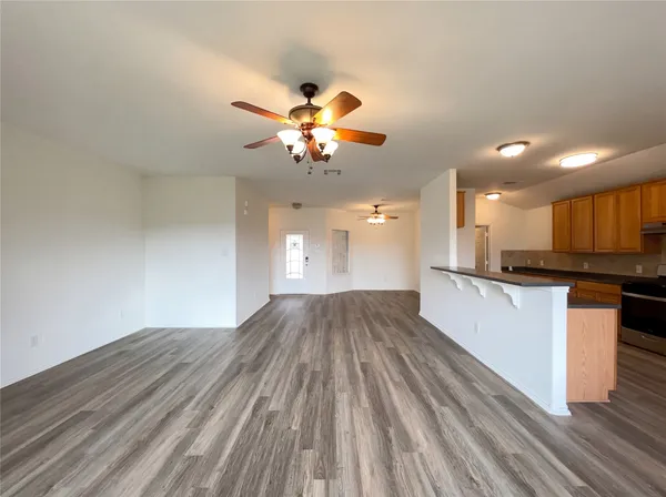 a view of kitchen and empty room with wooden floor