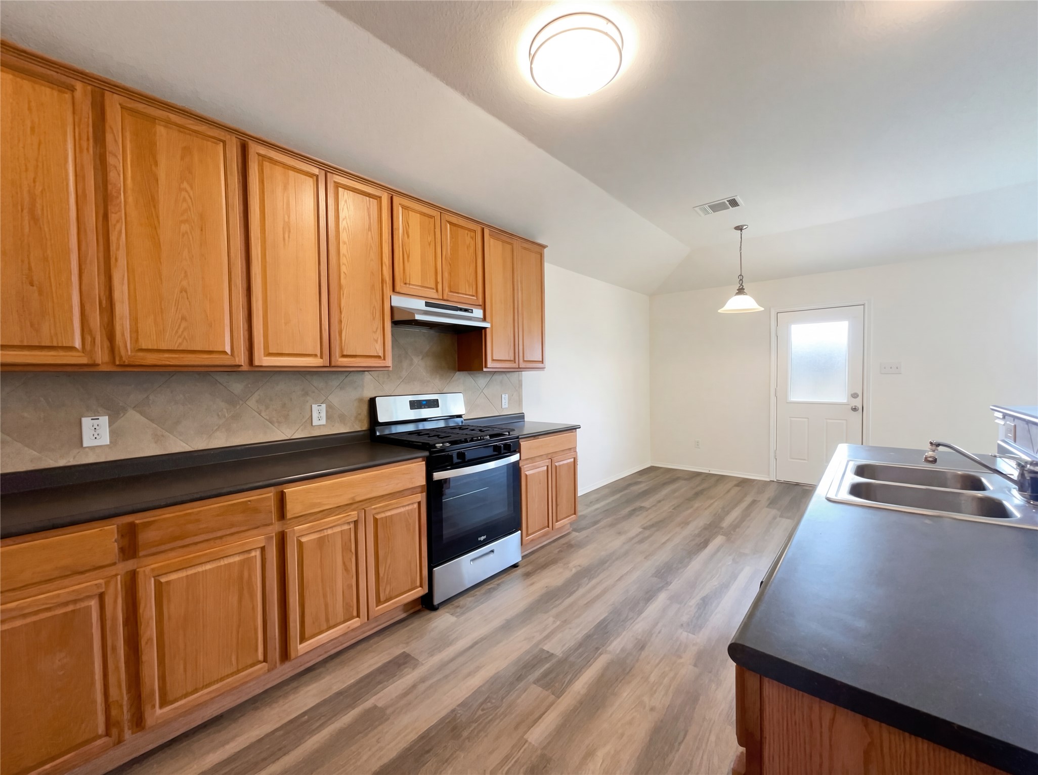 506 Gettysburg Loop Elgin, TX 78621 - Photo 20 of 39 a kitchen with stainless steel appliances granite countertop wooden cabinets a stove a sink and dishwasher with wooden floor