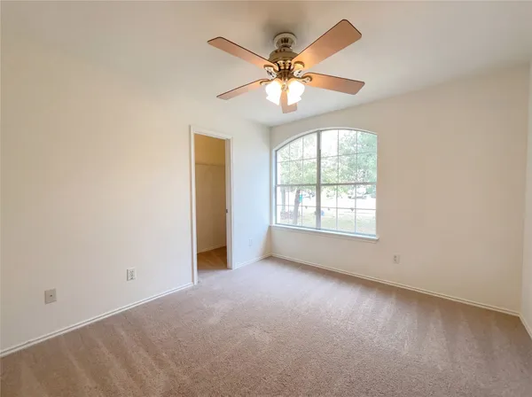 an empty room with a window and a fan