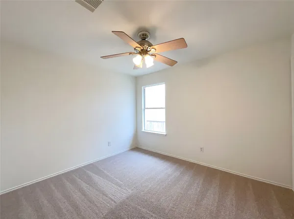 an empty room with windows and fan