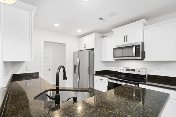a kitchen with stainless steel appliances granite countertop a refrigerator a stove and a sink with wooden floor