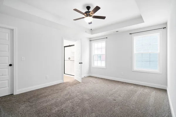 an empty room with a ceiling fan and carpet
