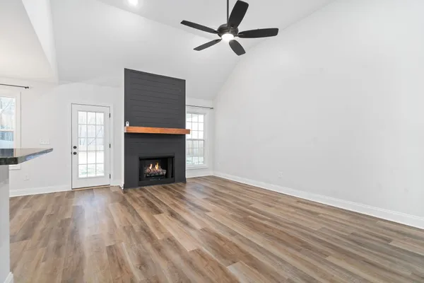 a view of an empty room with wooden floor and a ceiling fan
