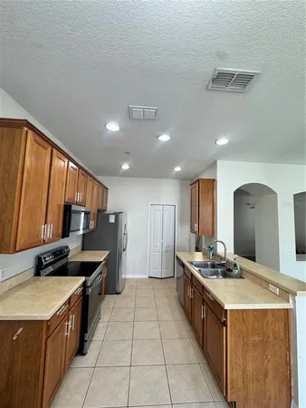 a kitchen with stainless steel appliances granite countertop a stove top oven a sink dishwasher and a refrigerator with wooden cabinets