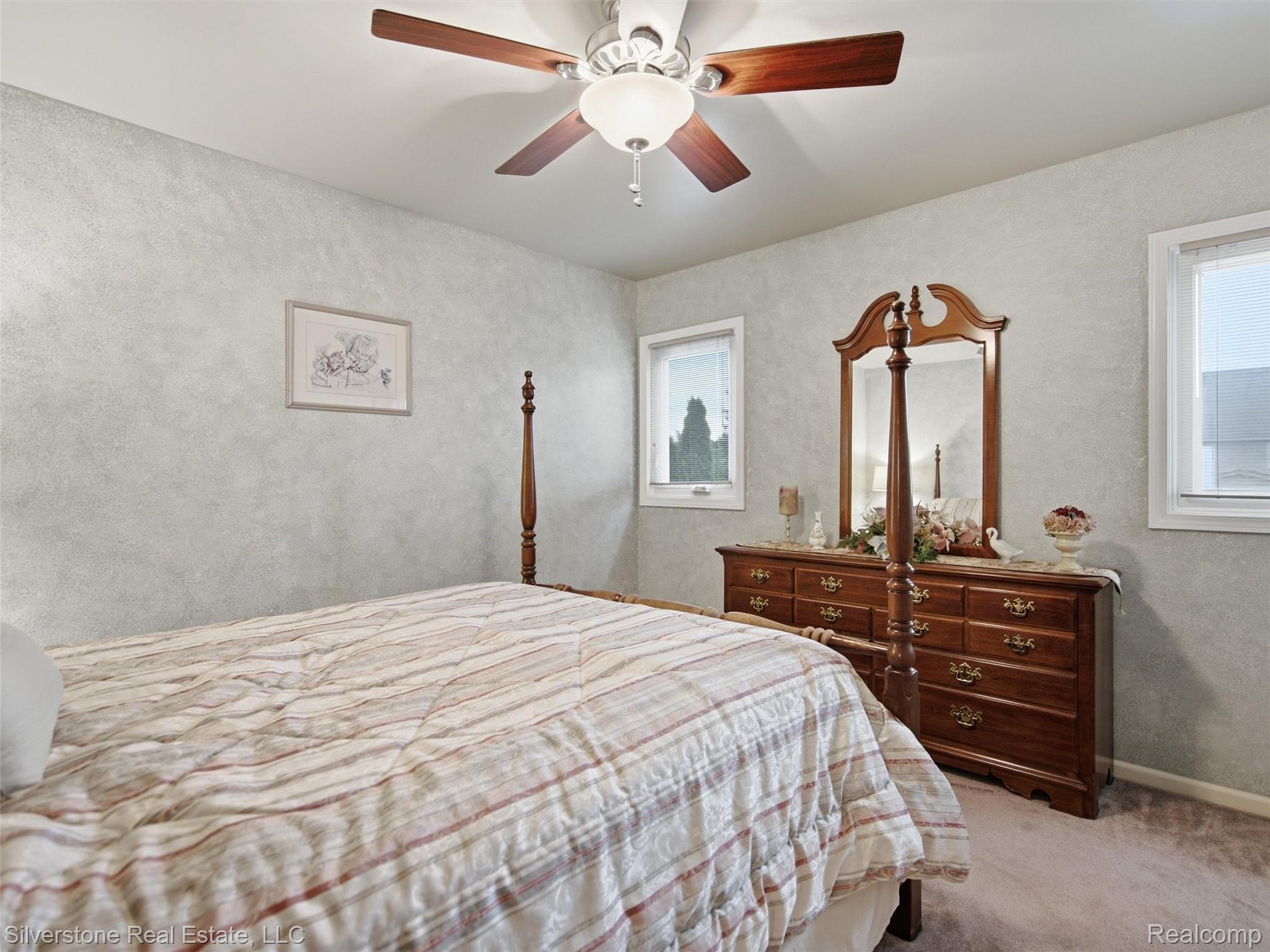 6577 Edith Court Troy, MI 48085 - Photo 39 of 61 Carpeted room featuring a ceiling fan with integrated lighting, two windows with white trim, and textured wall finishes