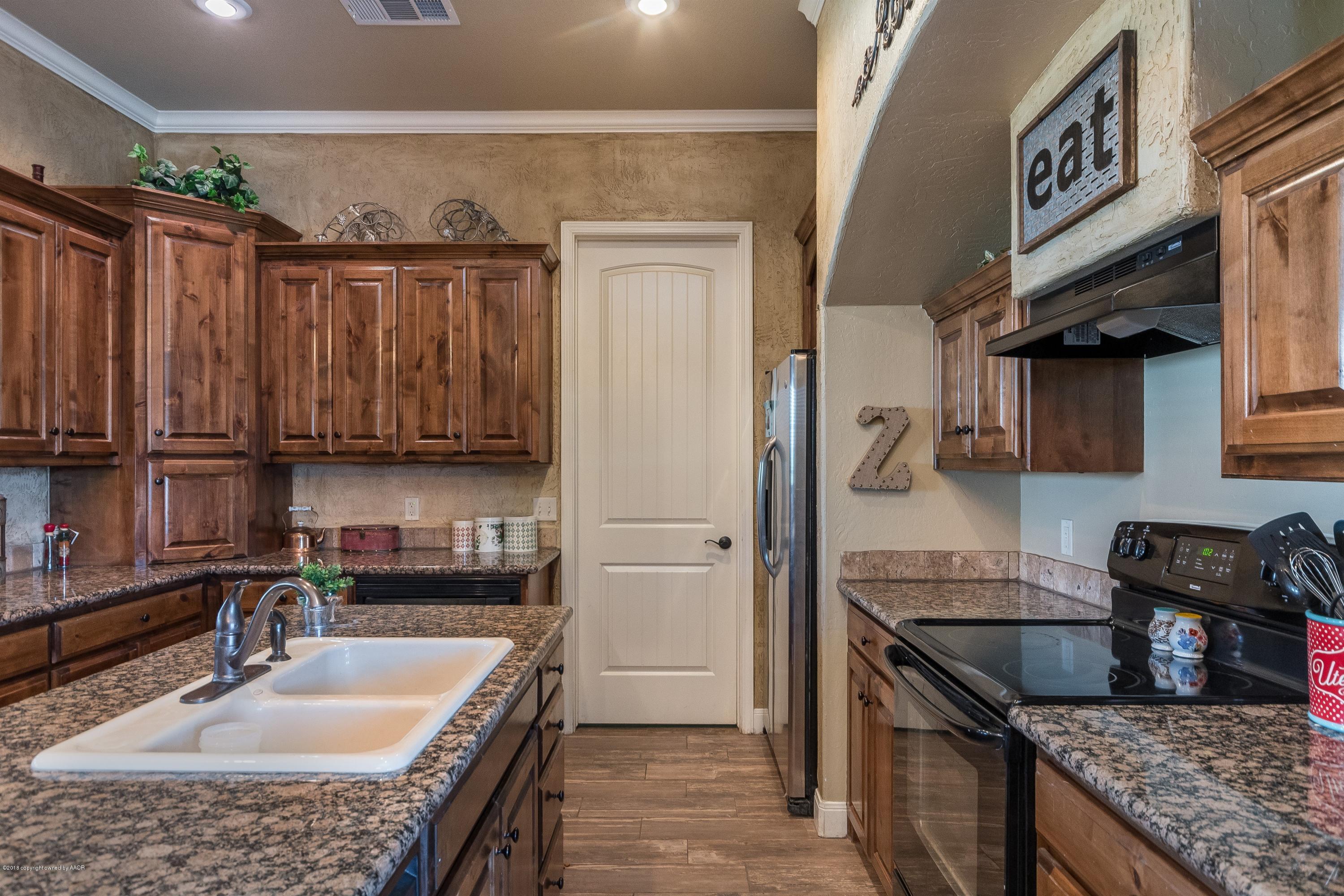 3909 Arden Road Amarillo, TX 79118 - Photo 9 of 20 a kitchen with granite countertop a sink a stove and a wooden cabinets