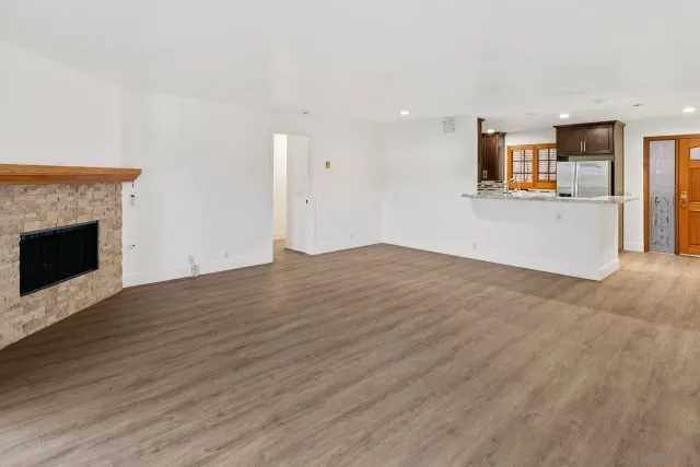 a view of empty room with wooden floor and fireplace