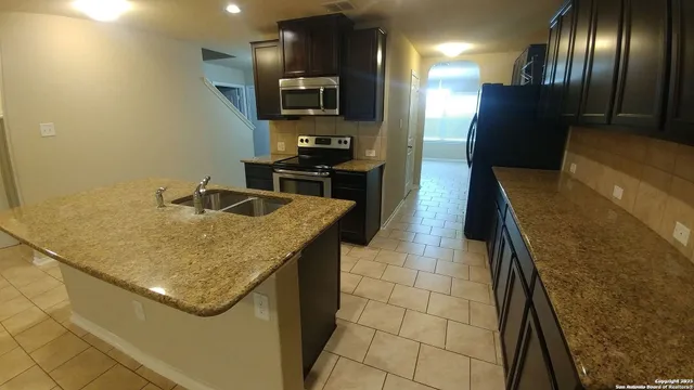 a kitchen with stainless steel appliances granite countertop a sink and a refrigerator