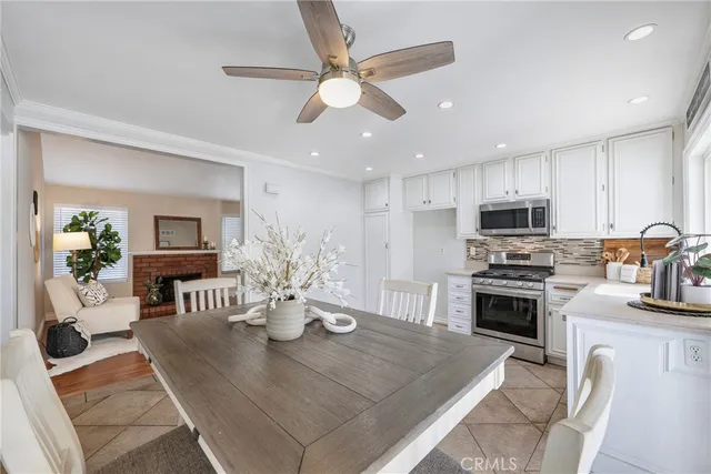 a open kitchen with stainless steel appliances granite countertop a stove top oven a sink a dining table and chairs with wooden floor