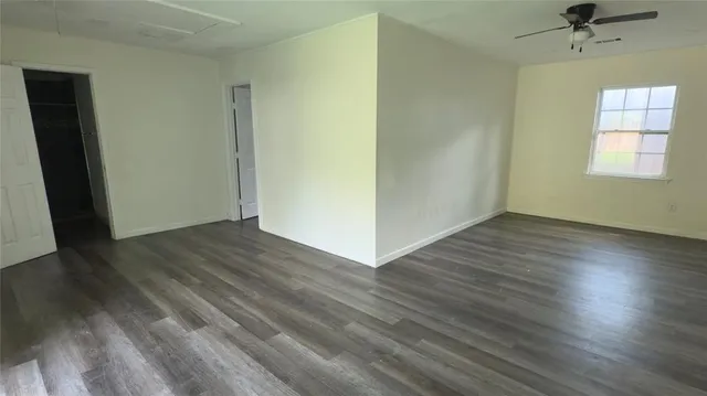 an empty room with wooden floor cabinet and windows