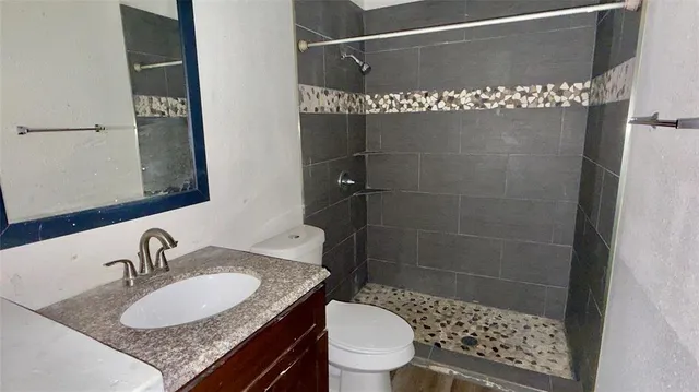 a bathroom with a granite countertop sink a mirror and a toilet