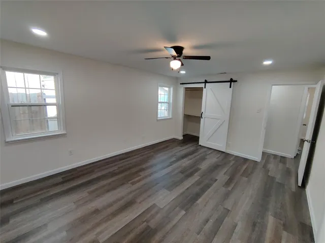a view of empty room with wooden floor and fan