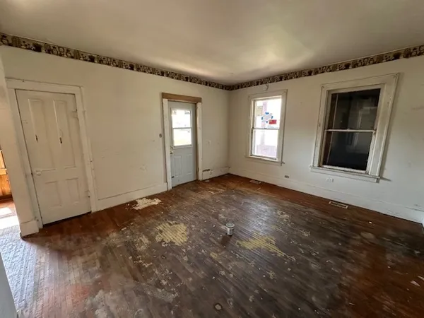 a view of an empty room with wooden floor and a window