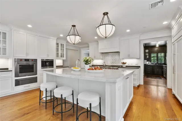 a large white kitchen with lots of counter space and stainless steel appliances