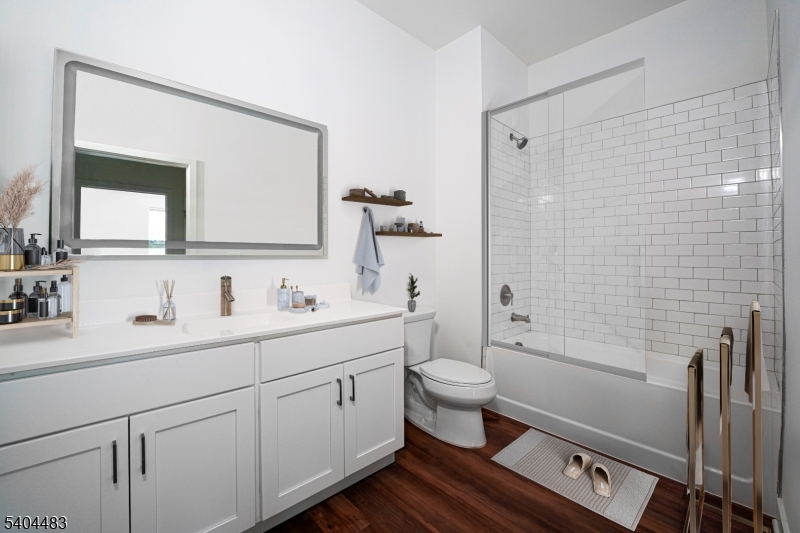 18 West Main Street, Unit 412 Bound Brook, NJ 08805 - Photo 7 of 27 a bathroom with a toilet a sink a mirror a shower a vanity and window